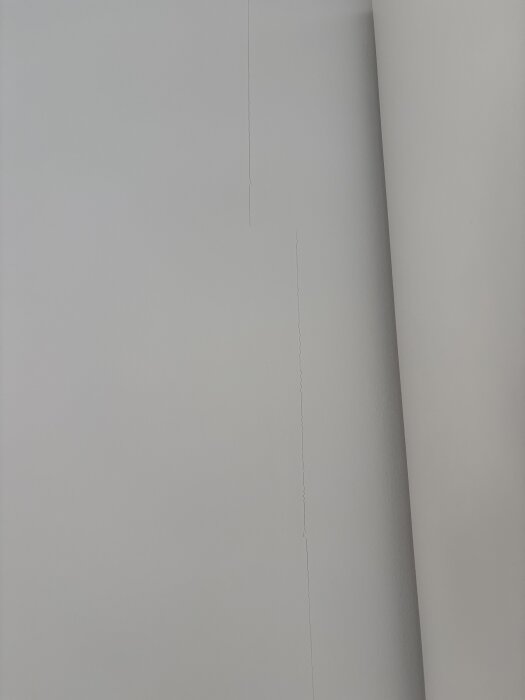 Sprickor på en ljus innervägg, som följer skarvarna mellan gipsskivor.