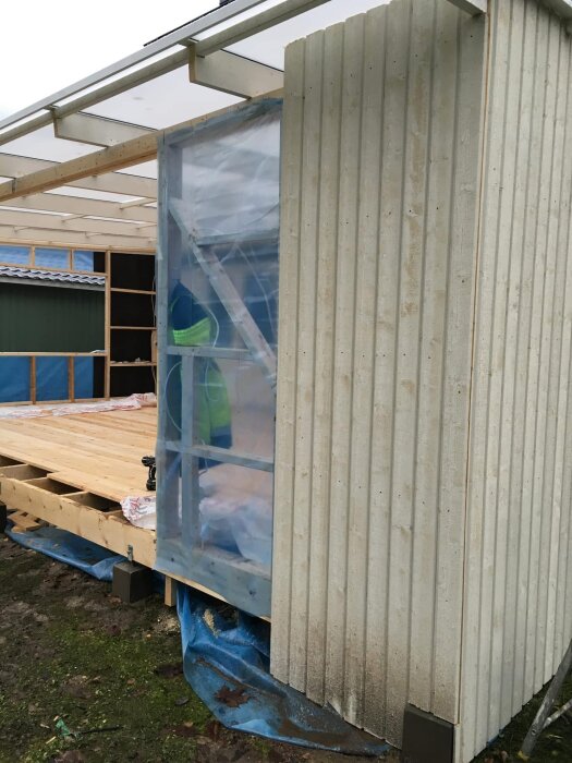 Byggnationen visar plastfolie på stommen med paneler spikade ovanpå, vilket ifrågasätts av inläggsförfattaren som en märklig byggmetod.