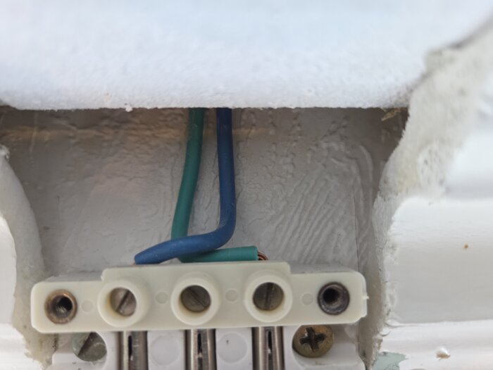 Elektrisk inkoppling med blå och grön kablage anslutna till ett vitt kopplingsblock.