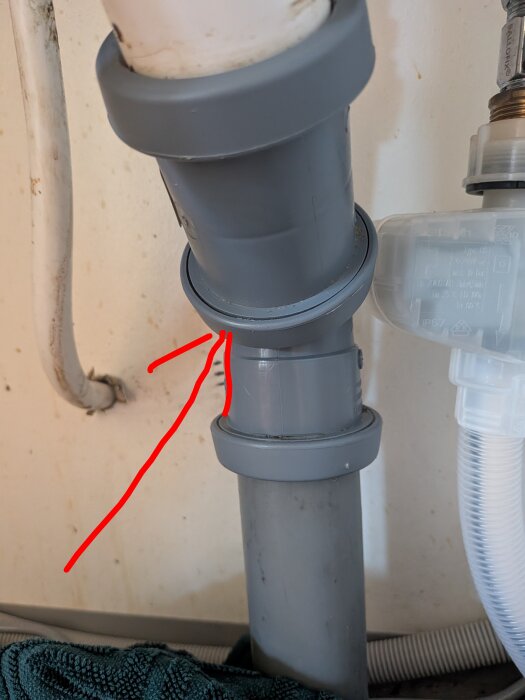 Underskåpsavlopp med grå rörkoppling som inte tätar, markerad med röda pilar. Oro för otät anslutning vid rörens sammanfogning.