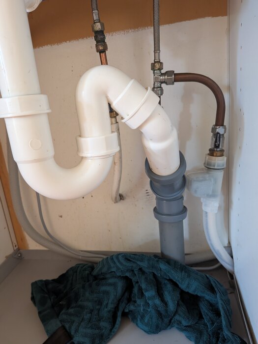 Under diskbänken med VVS-rör och en anslutning som inte tätar.