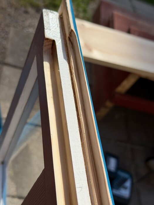 Närbild av frästa träbågar under renovering av ett ytterfönster, visandes precision i hantverket.