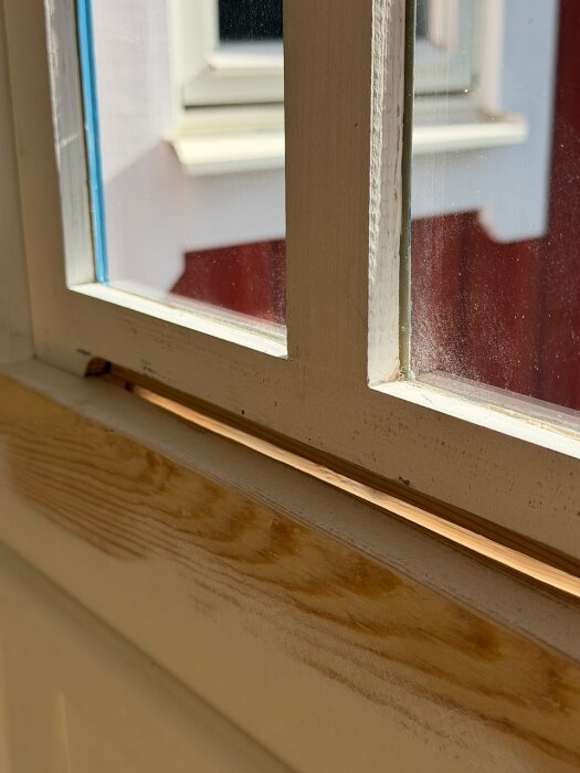 Närbild på ett fönster vars karm har bearbetats, slipad och grundad träyta syns tydligt.