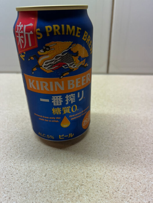 En burk Kirin Beer med blå etikett och gyllene drake, på en ljus yta.