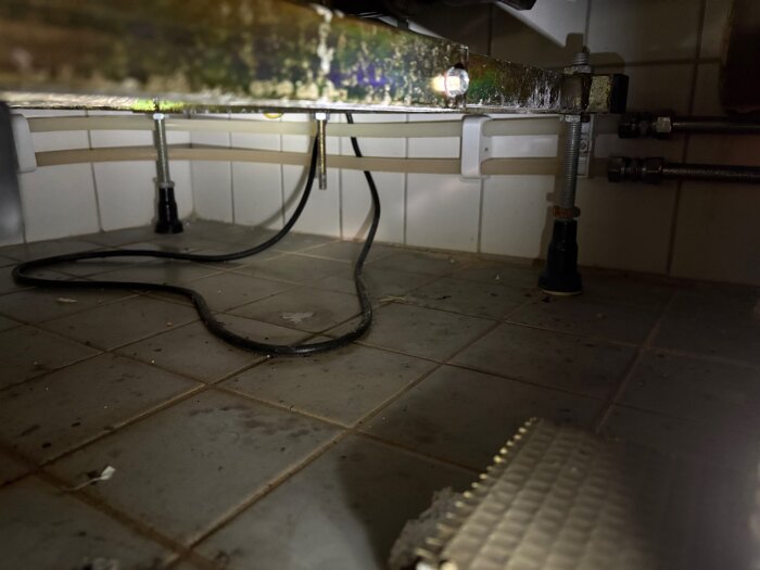 Kabel ligger direkt på golvet under badkar.