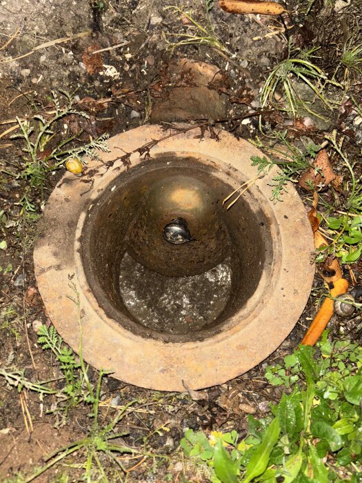 Gamla rör i marken omgivna av jord och växtlighet.