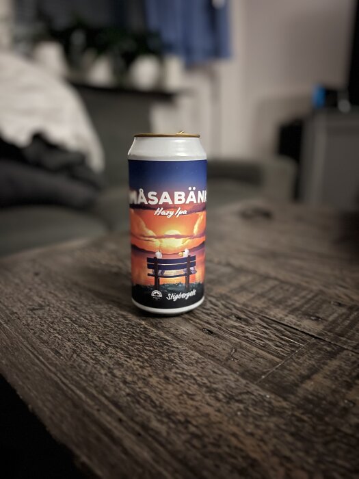 Ölburk märkt "Måsabänk Hazy IPA" med solnedgångsdesign, från Stigbergets, på ett rustikt träbord.