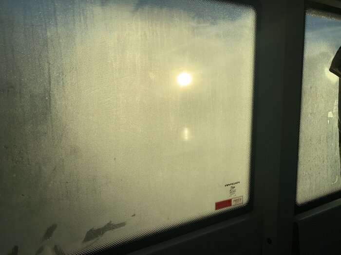 Immat fönster med solstrålar som skiner igenom, vilket försvårar utsikten i ett skärgårdsområde.