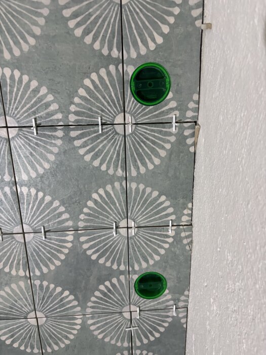 Gröna cirkulära hål skurna i kakel med blomliknande mönster, täckta med distanser, visar användning av diamant hålsågar.