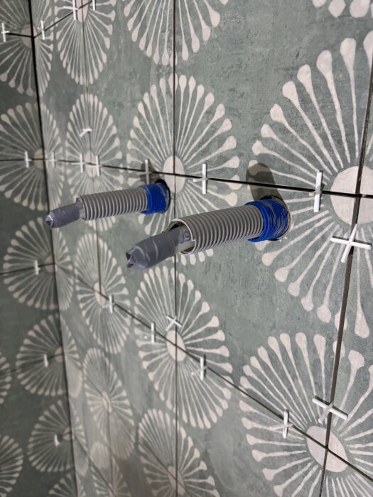 Vinkelslipens diamant hålsågar borrar perfekta hål i kakelplattor med blomdesign, stödda av kakelkryss för jämn fogning.