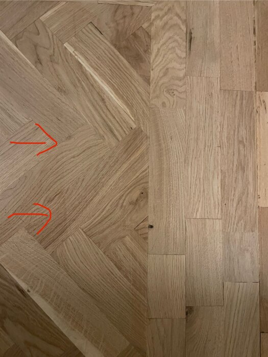 Närbild av fiskbensparkett med pilar som pekar mot glipor mellan stavarna och ojämnheter i övergången mellan nytt och gammalt golv.