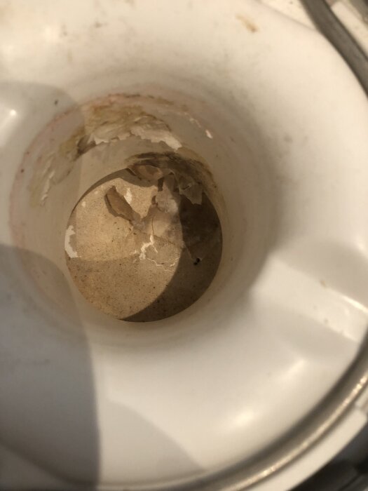 Insidan av en vattenkokare med avlagringar och rostfläckar på botten och kanterna.