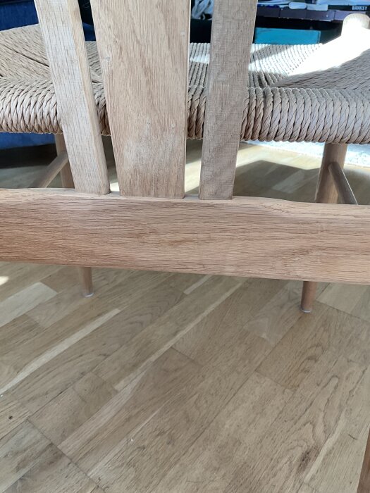 Matstol i trä med flätad sits, fotograferad mot ett trägolv. Träslaget kan eventuellt vara ask.