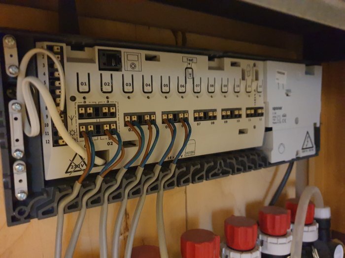 Uponor C-56 reglercentral med synliga kablar och anslutningar innanför skalet.
