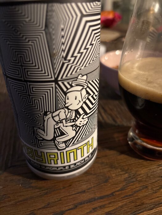 En burk med etiketten "Labyrinth" och ett glas Black Ale på ett träbord.