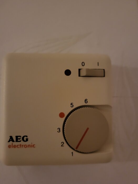 Gammal AEG elektronisk termostat för golvvärme med temperaturreglage och på/av-knapp.