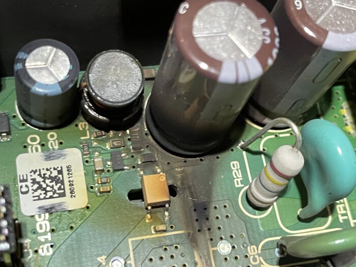 Kretskort med flera kondensatorer och en motstånd med färgkodade ringar, markerad plats A29.