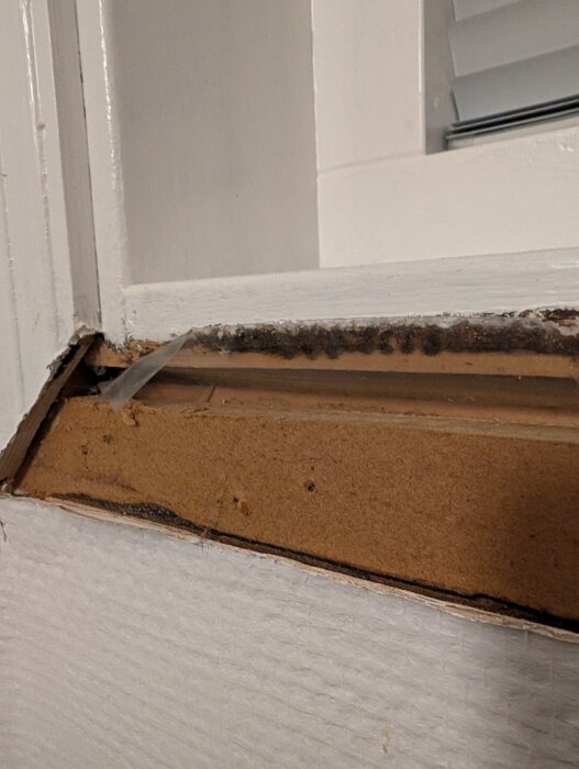Fönsterkarm med borttagen ram, exponerat trämaterial och ojämn yta kring skarv, redo för spackling och renovering.