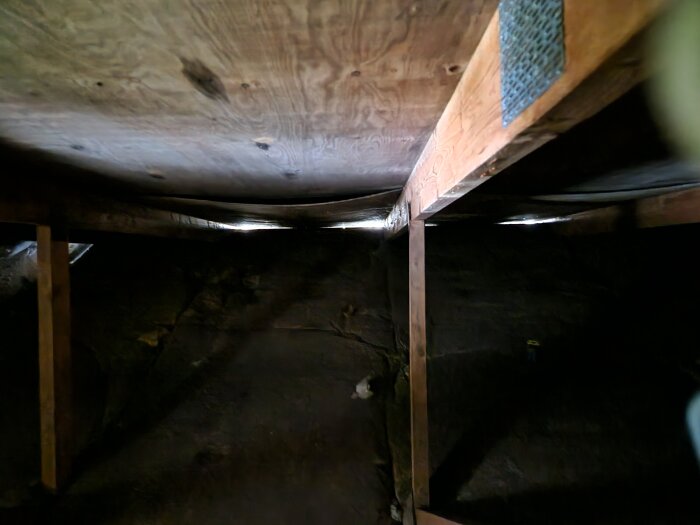 Plywoodtak inuti ett 70-talshus, hängande mellan takstolar, påverkar ventilationen. Duk och läkt syns ovanpå.