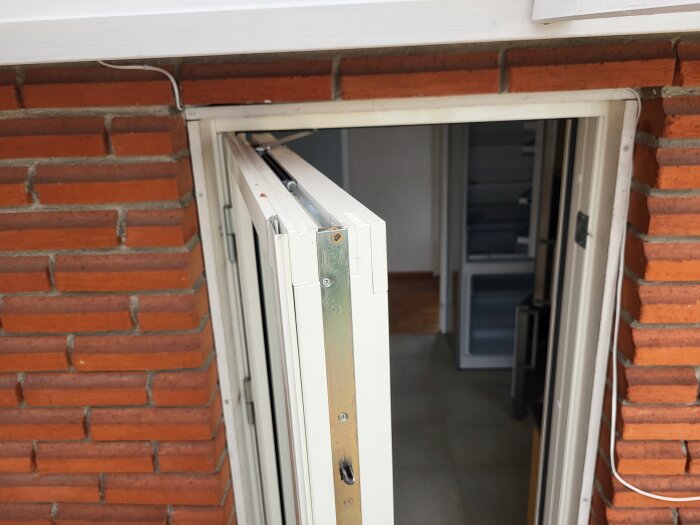 En öppen fönsterkarm i tegelvägg med synlig spanjolett och mätmarkeringar.