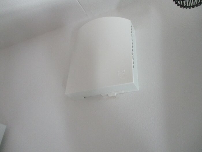 Vit innervägg med en Aero Flexit ventil monterad, synlig i närbild.