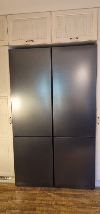 Dubbla rostfria kylskåp från LG inbyggda i ett kök med ljusa träluckor och parkettgolv.