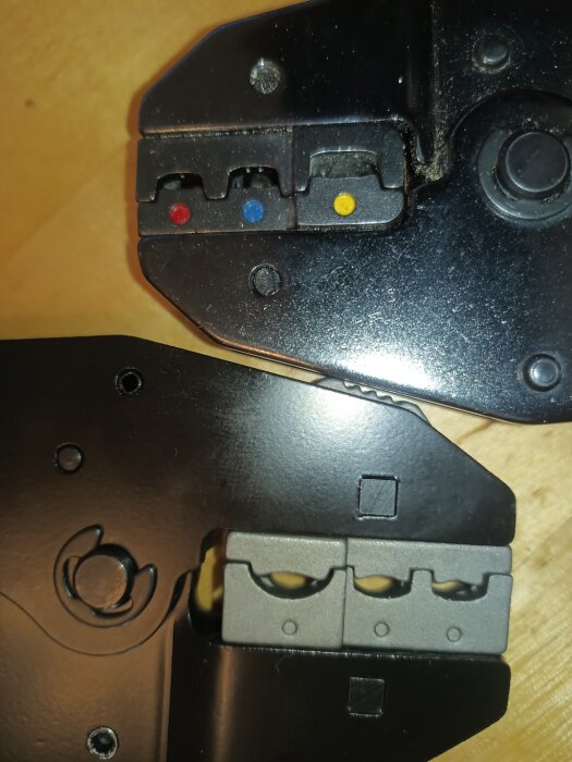 Krimptångar med utbytbara backar, en med färgkodade hål för röd, blå och gul kabelsko, den andra med grå backar.