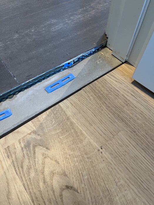 Täskel har tagits bort från en dörröppning, visar två golvytor och blå plastdetaljer. Trögelser och ansvar för problemet diskuteras.