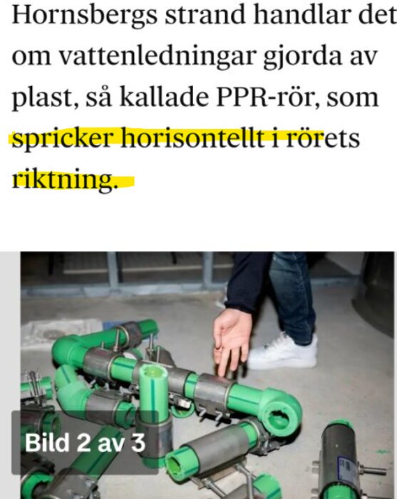 Grönt PPR-rörsystem med stålmanschettrer på en golvyta, en hand pekar mot rören.