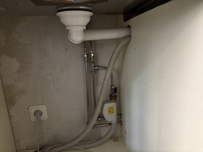 Rör och kopplingar under diskbänk med ballofixventil och avloppsrör för diskmaskin, plats för eventuell tvättmaskinsanslutning.