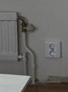 Typiskt tvårörssystem för elementrör mot vägg, kontaktuttag synligt i närheten.