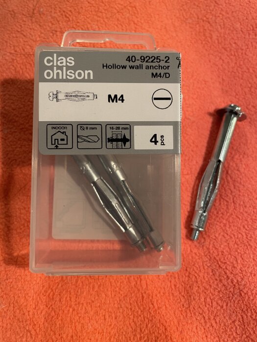 Förpackning av metallexpander, M4, från Clas Ohlson på röd bakgrund med en expander utanför förpackningen.