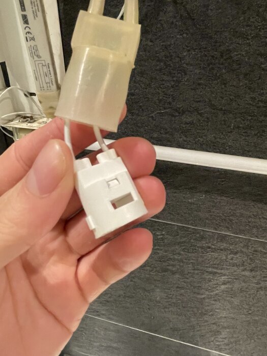 Kopplingskontakt med tätningar för anslutning av drivdon och lysrör, hålls i en hand.