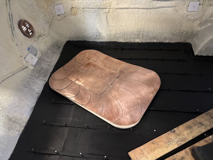 Kopparplåt på svart yta i vagnen, synliga skruvar och ventil.