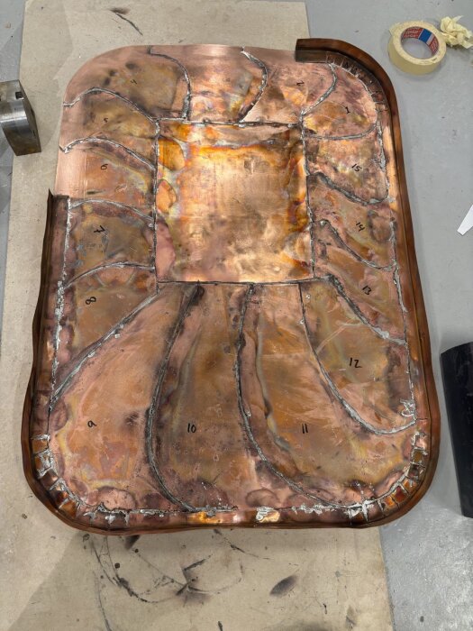 Kopparplåt med lödda fogar och nummermarkeringar; del av gnistskydd i byggprojekt.