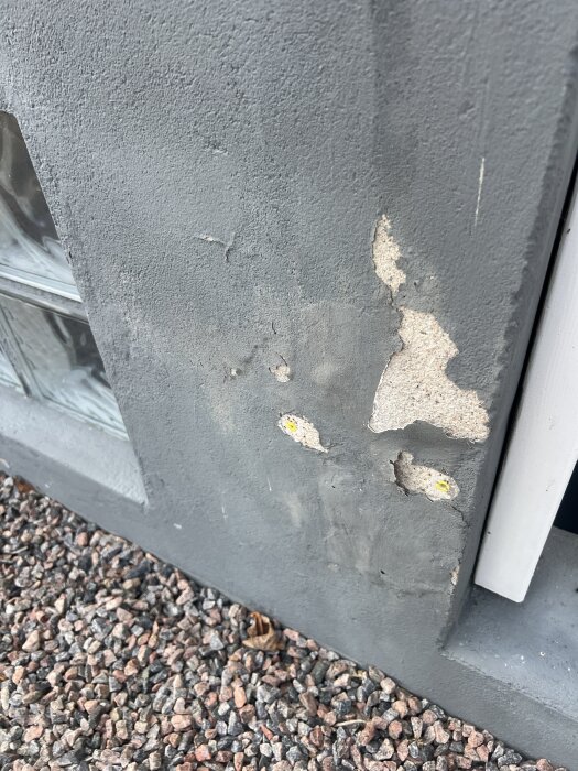 Färgen på betonggrunden har flagnat av på flera ställen, med blottlagd yta i behov av reparation och ommålning.