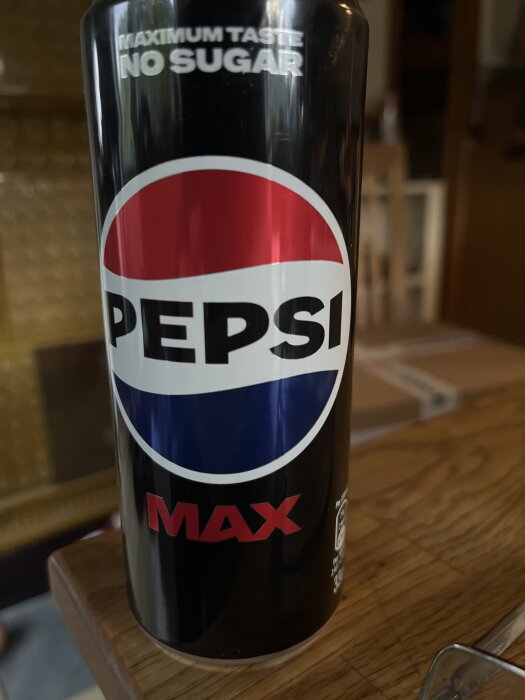 En burk Pepsi Max med texten "Maximum Taste, No Sugar" på ett träbord.