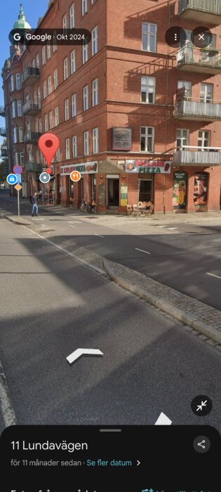 Gatukorsning vid röd tegelbyggnad med Pallani Pizza på hörnet, cykelbana och trottoar synliga, diskussion om trafikregler.