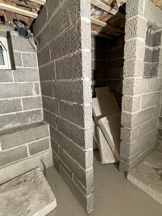 Byggarbetsplats med ofärdig duschhörna i betongblock, synliga rör och takdetaljer.