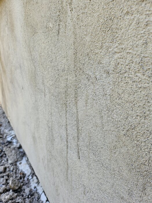 Källarvägg med sprucken och ojämn puts, grovkornig textur.