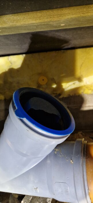 Blåfogad PVC-rörkoppling med blöt yta, kanske täckt av plast, visar en hel ledning i ett byggprojekt.
