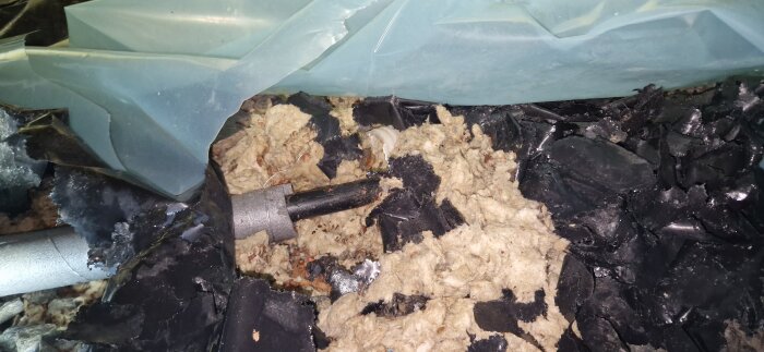 Svart plaströr omgiven av isoleringsmaterial och plast.