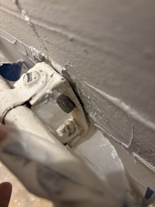 Vägg med vita rör och en stor, lös skruv som inte kan lossas.