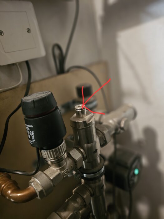 Vattenkopplingar med ventil och röda pilar som markerar avstängningspunkter för att byta ventilbröstet.