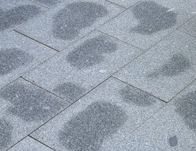 Blöta fläckar på stenläggning efter urgrävning och bärlagerfyllnad.