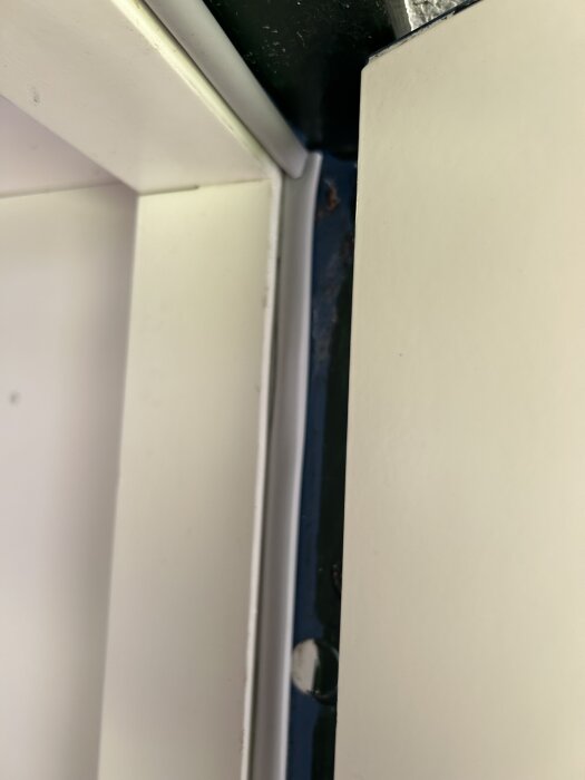 Bild på dörrkarm med monterad tätningslist för att stänga ute kyla. Visar justering med maskinskruv i hörnet.