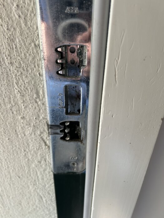 Närbild på en dörrkarm med metallinfästning där dörrhaspen går in, används för att täta och justera passform mot kylan.