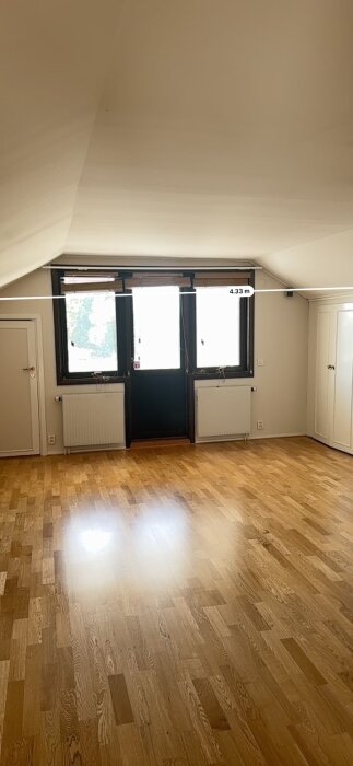 Stor rum med trägolv och takfönster, mätning på 4.33 m, planeras delas till två mindre sovrum.