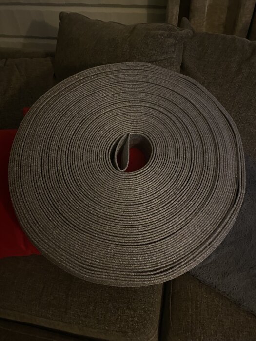 Grå, spiralformad rulle med isoleringsmaterial på en soffa.