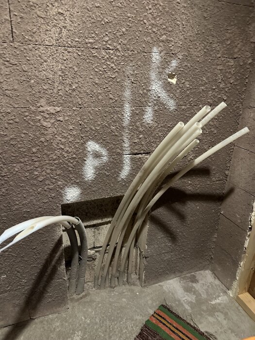 Golvvärmerör som sticker ut från en vägg i ett halvfärdigt badrum, med en ursparing synlig i väggen.